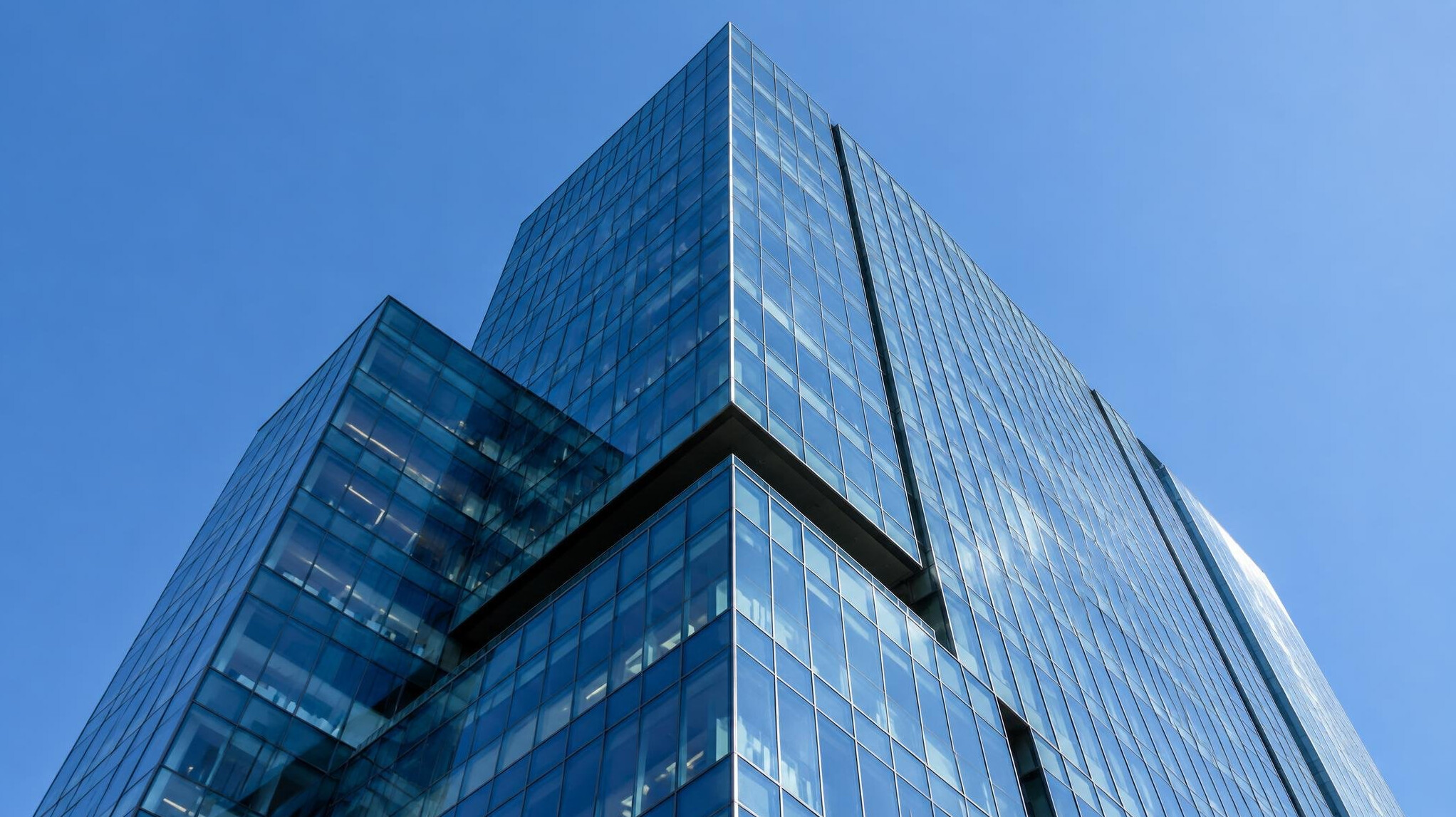 Glass facade of a corporate office tower against a blue sky